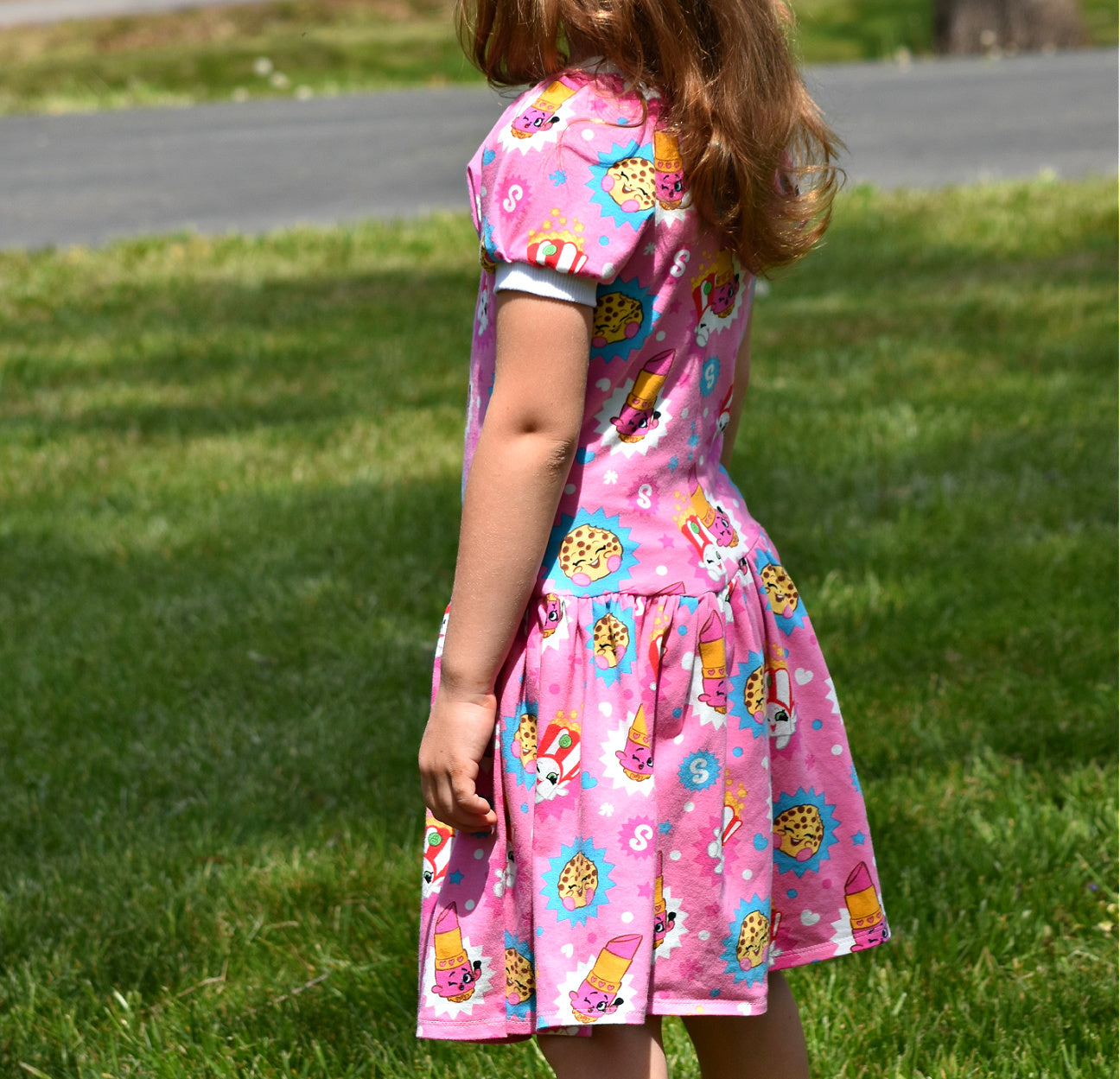 Amelie raglan dress, pdf sewing pattern by Frocks & Frolics. Raglan puff sleeves and ribbed neckband. Low gathered waist. Dress in Jersey with kiddo pink print and white trim.