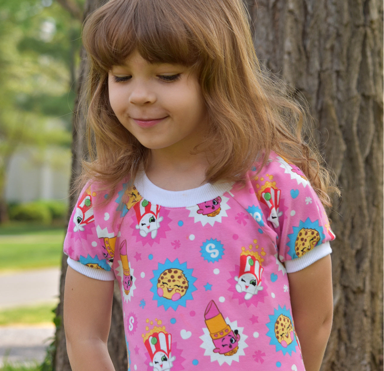 Amelie raglan dress, pdf sewing pattern by Frocks & Frolics. Raglan puff sleeves and ribbed neckband. Low gathered waist. Dress in Jersey with kiddo pink print and white trim.