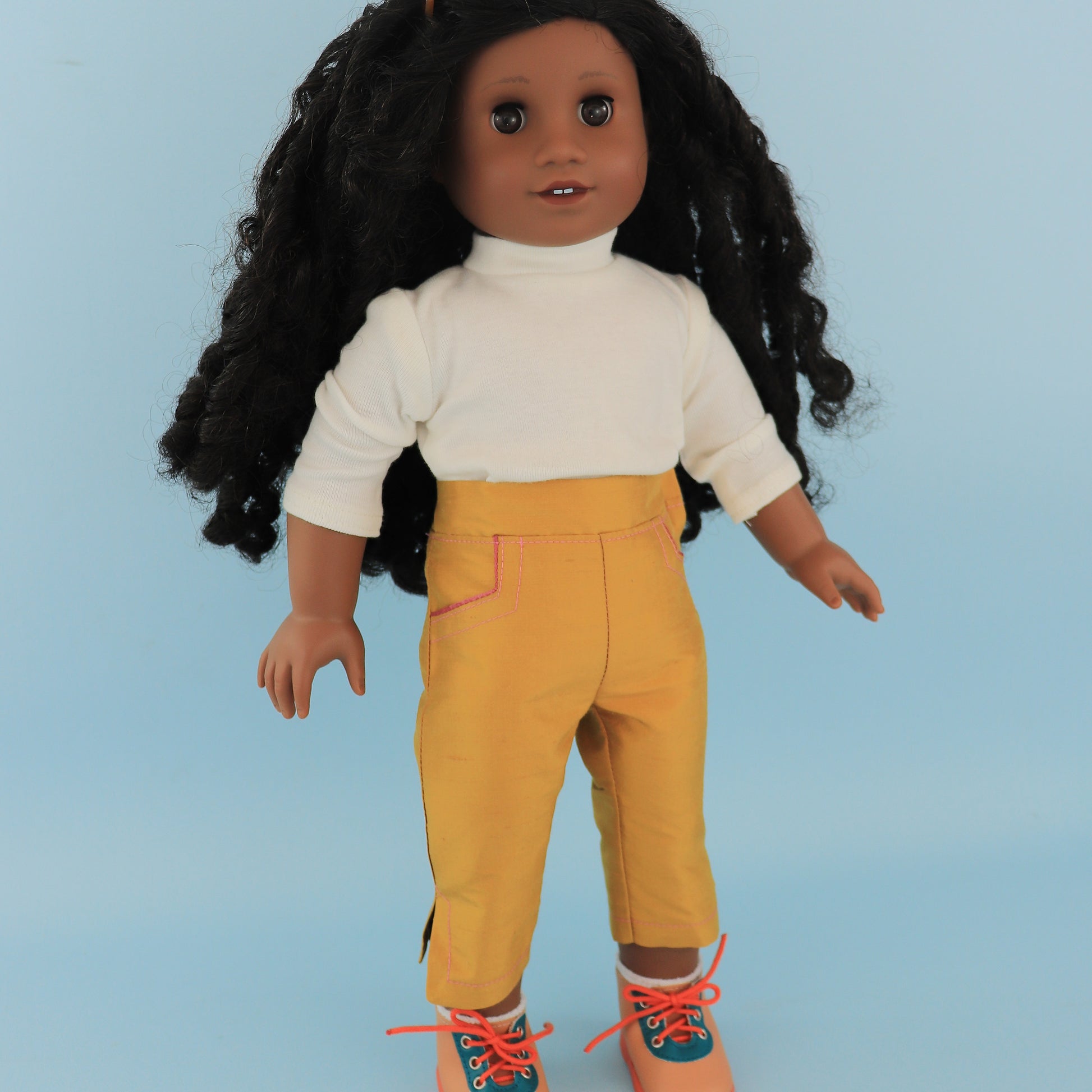 Audrey Capri pants, American girl pdf sewing pattern. Fits 18 inch dolls. Faux pockets, flat front waistband, elasticated in the back. Velcro closure. Comes with video tutorial. In nmustard silk.