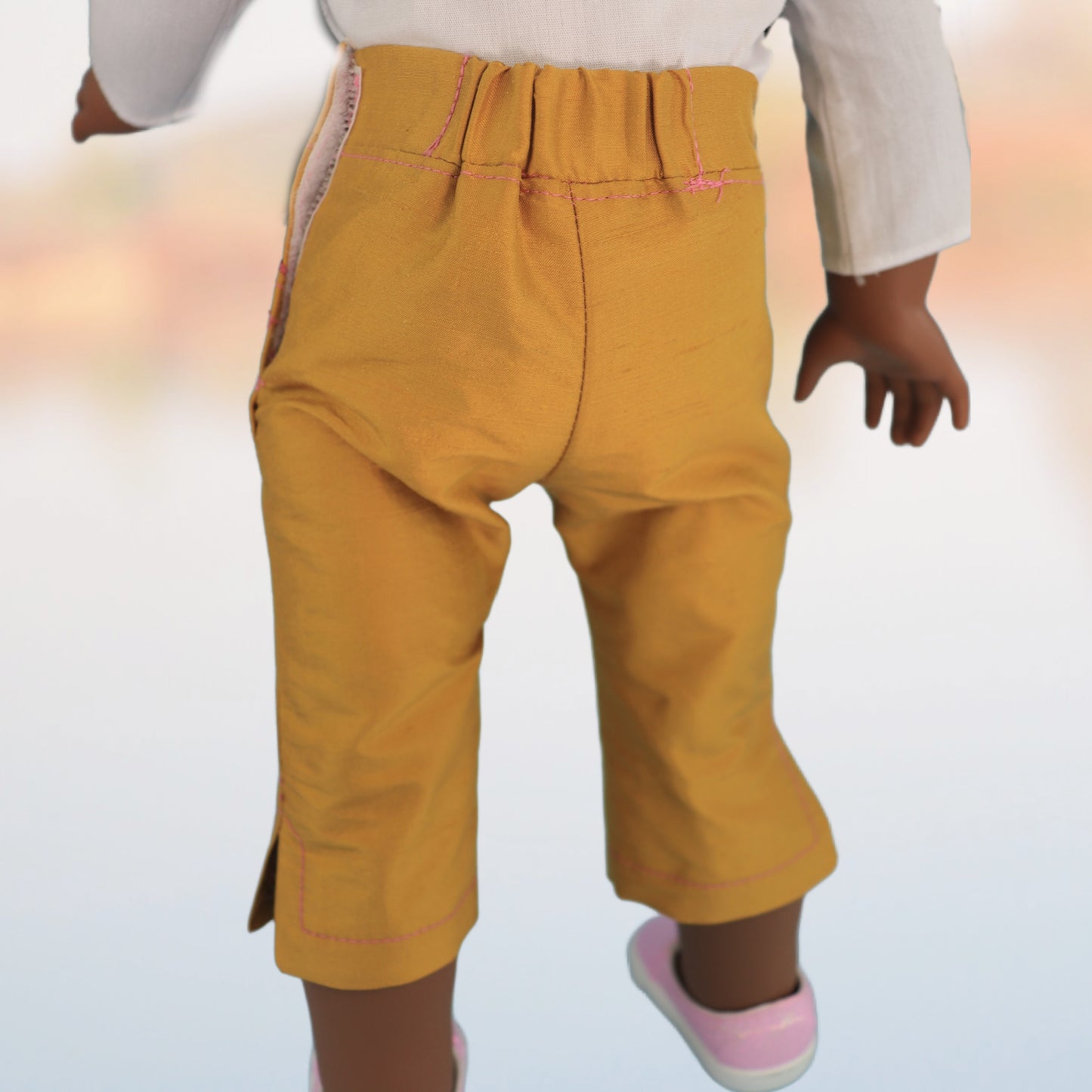Audrey Capri pants, American girl pdf sewing pattern. Fits 18 inch dolls. Faux pockets, flat front waistband, elasticated in the back. Hem with slit made in mustard dupion silk. Comes with video tutorial. Back view.