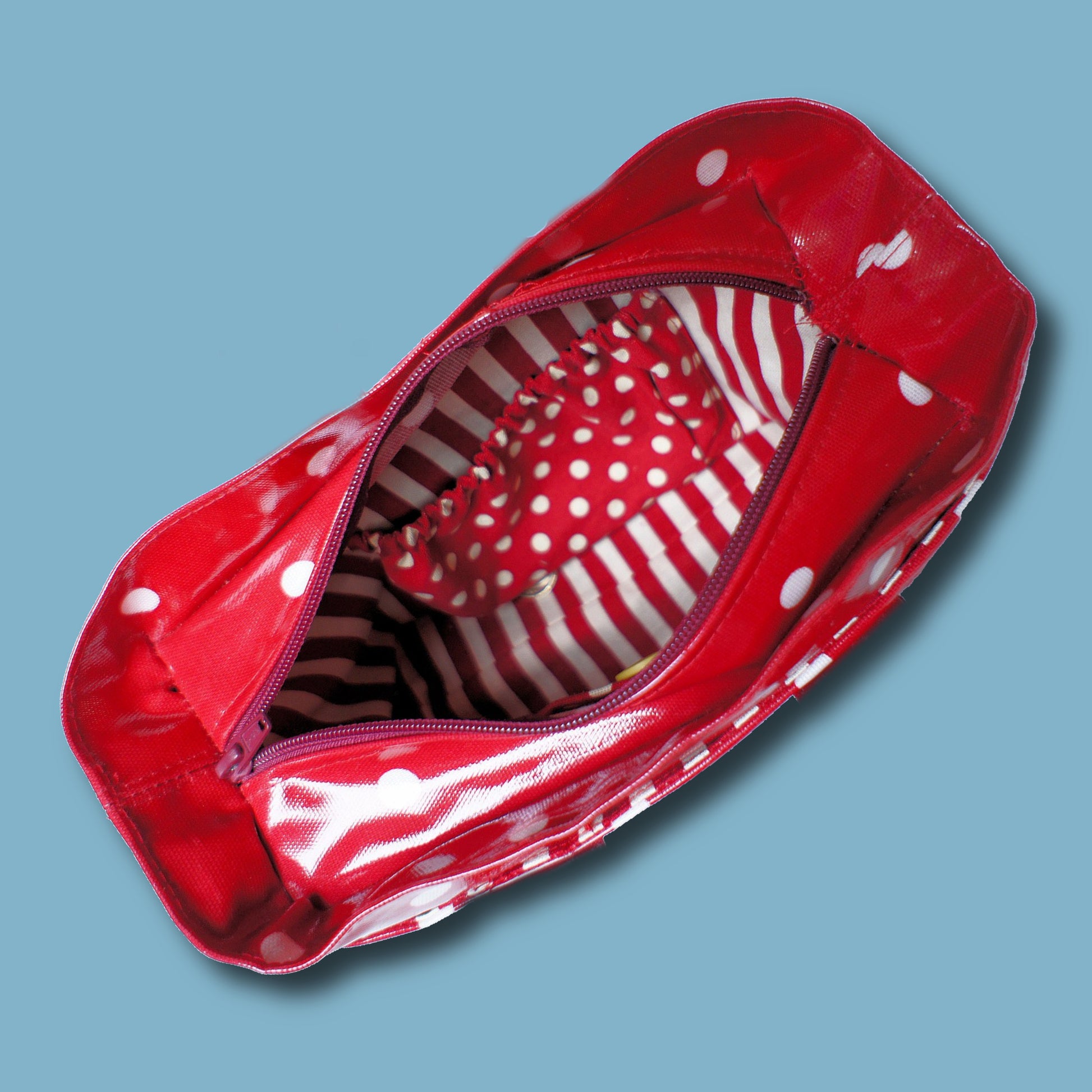 Mini tote bag in red oil cloth with white polkadots. Sneak peak into the bag through the open zipper. This pdf sewing pattern comes with a video guide.