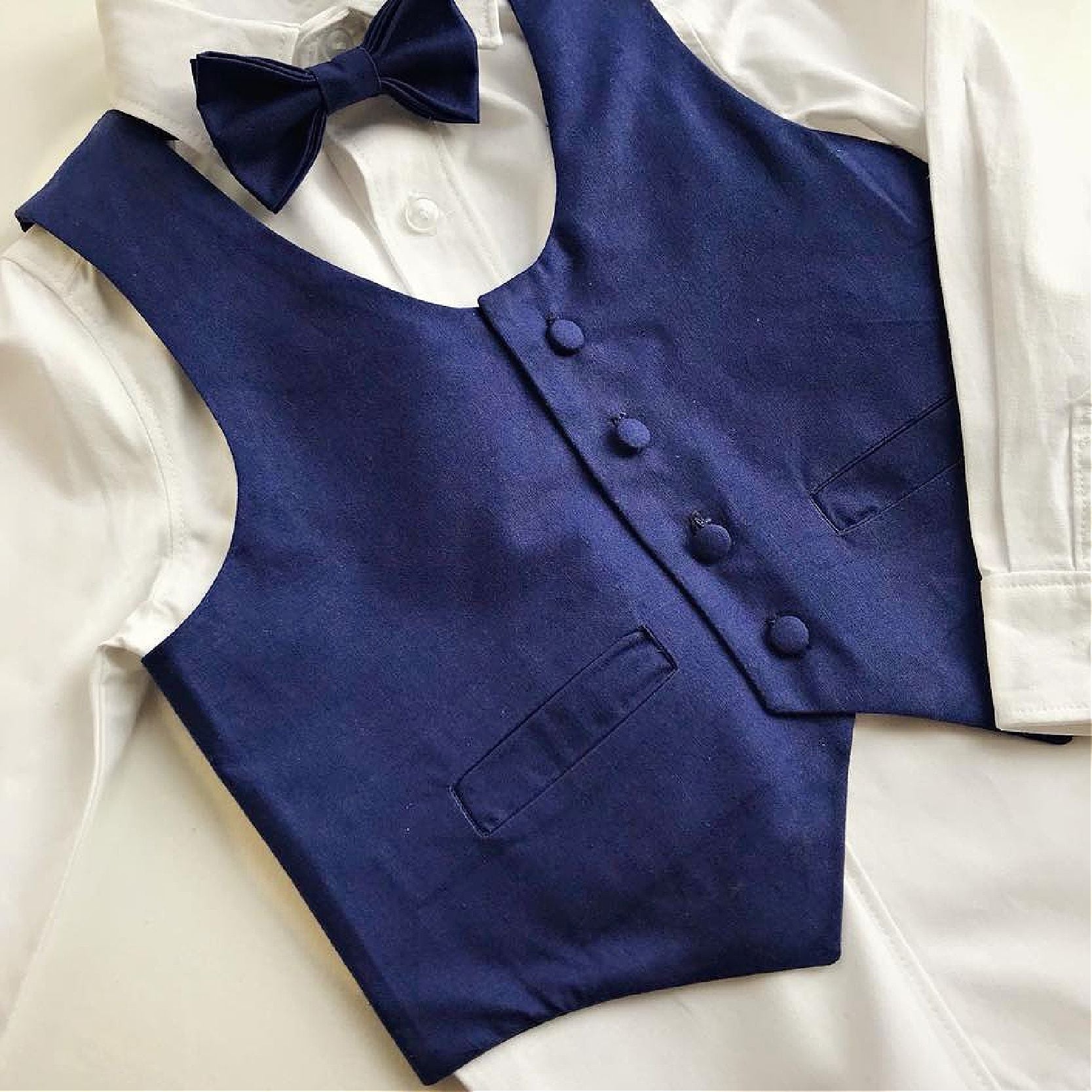Brooklyn waistcoat, pdf sewing pattern by frocks and frolics. Fully lined with tie backs. Flat view of a page boy outfit. Blue silk waistcoat with white dress shirt and matching Dicky Bow. Includes a free video sewing course.