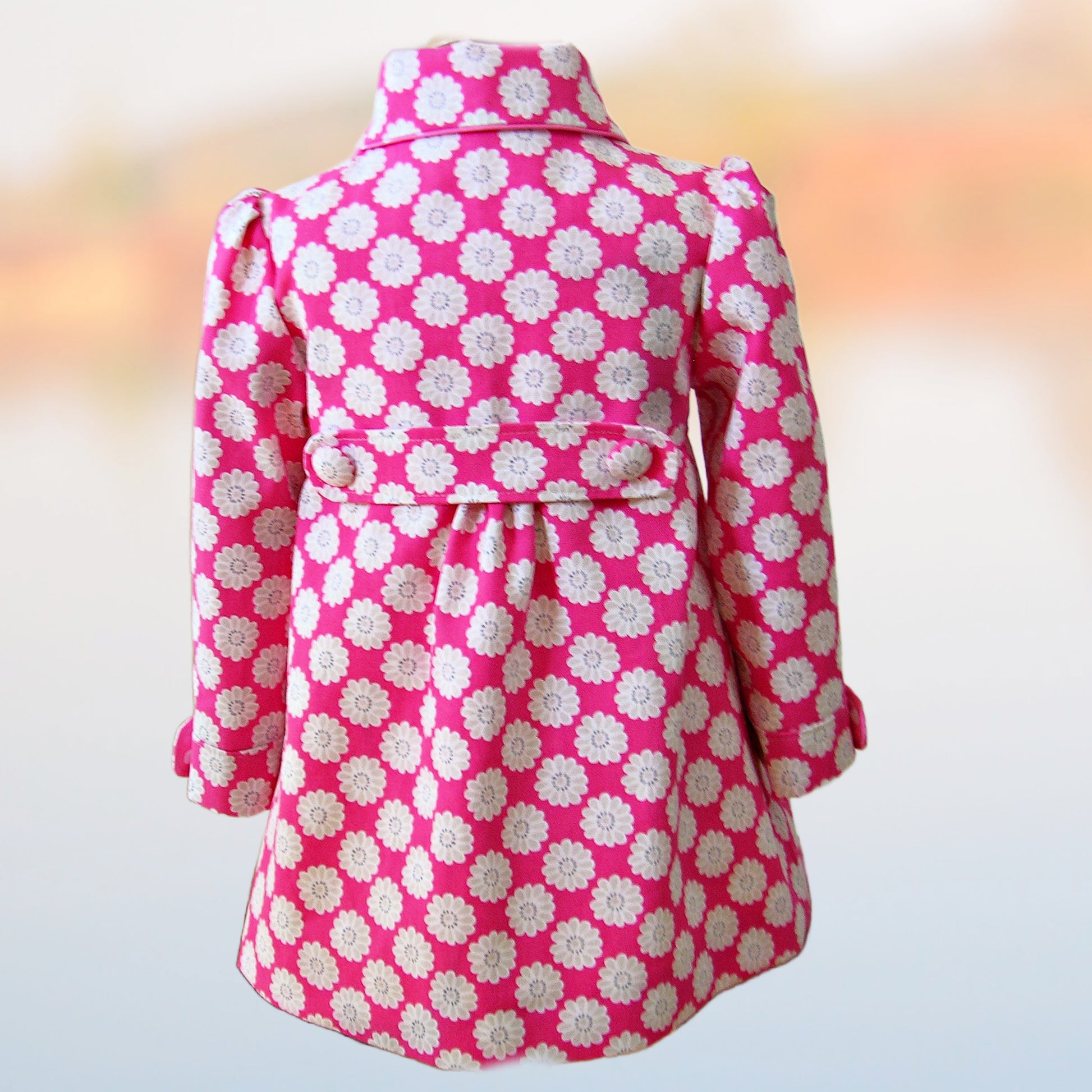 Charlotte girls coat, pdf sewing pattern by Frocks & Frolics. In upholstery cotton with large flower print. Long puff sleeves with cuffs and tabs. Featuring a yoke and rounded collar. Back view of the tab and buttons. Includes video tutorials.
