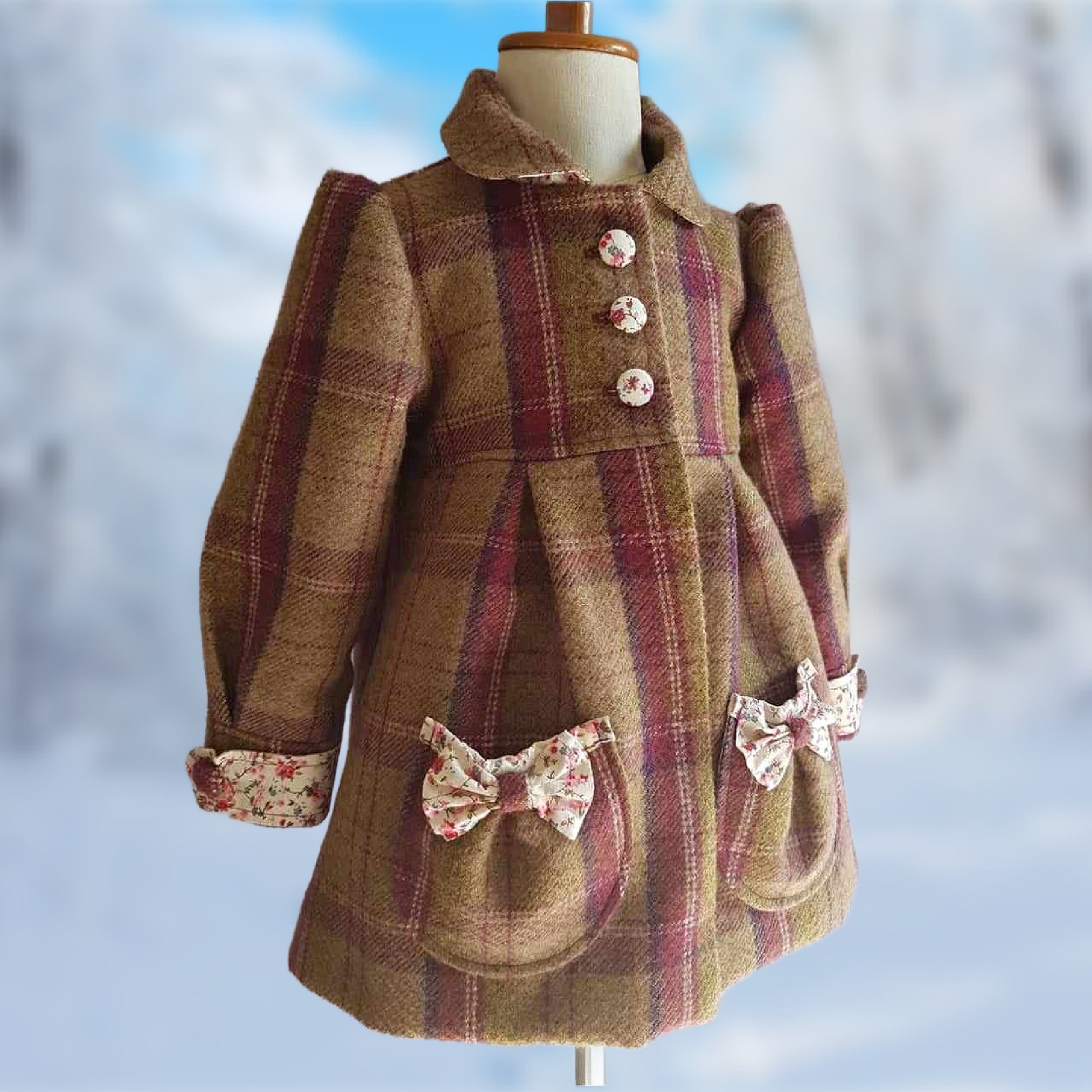 Charlotte girls coat, pdf sewing pattern by Frocks & Frolics. In tartan wool with printed cream cotton and tiny flowers for the tabs and buttons. Long puff sleeves with cuffs and tabs. Featuring a yoke and rounded collar.