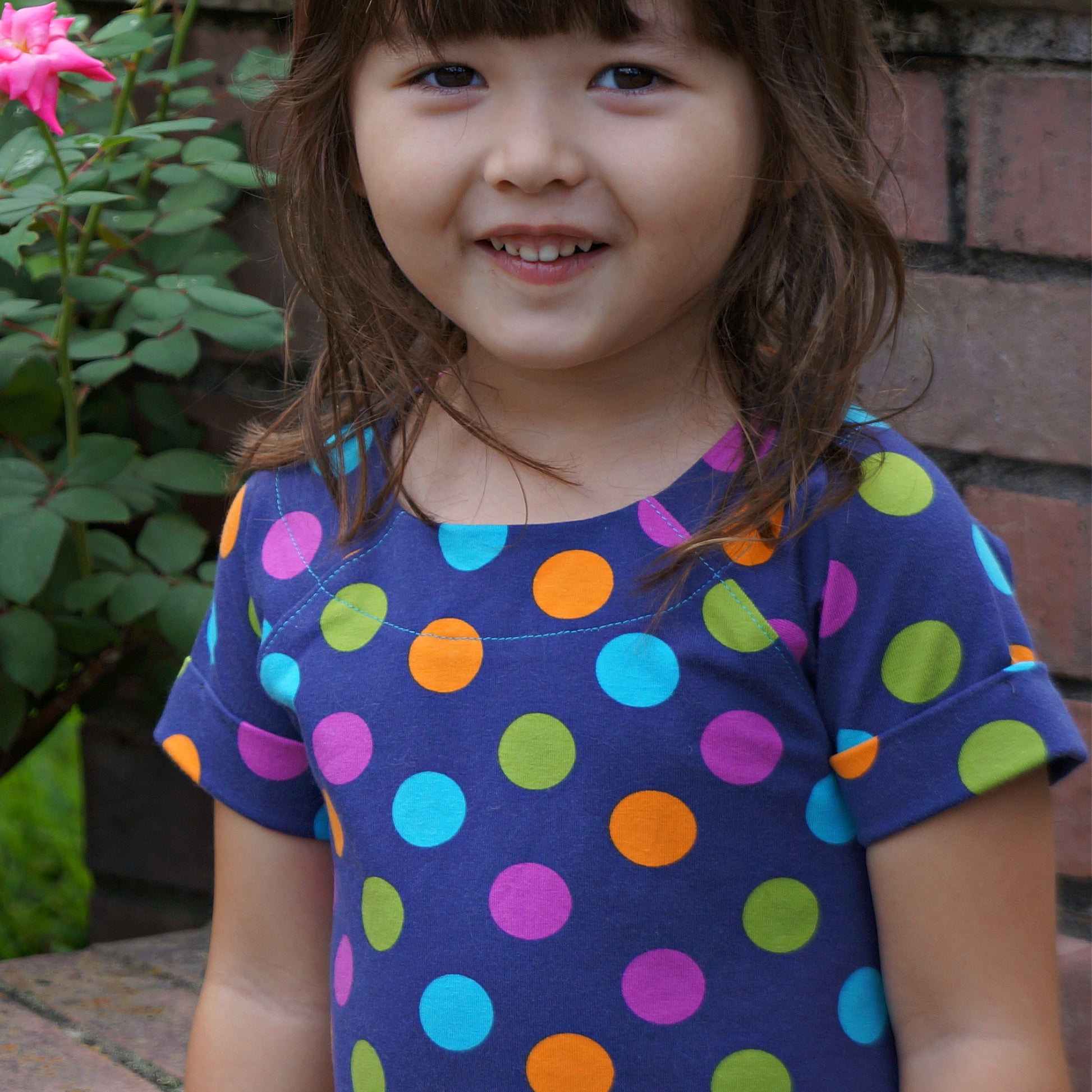 Daisy dress, pdf sewing pattern. Jersey dress with short raglan sleeves and faux turn up. The dress hasa KamSnap back closure and deep decoratove hem trim. The pattern comes with a step-by-step video tutorial. Close up of the neckline.