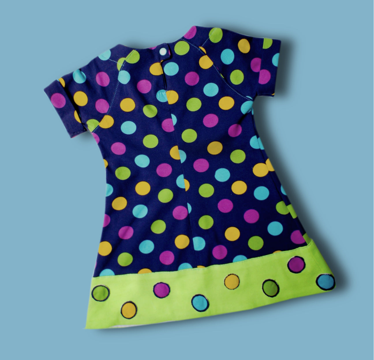 Daisy dress, pdf sewing pattern. Jersey dress with short raglan sleeves and faux turn up. The dress has a KamSnap back closure and deep decoratove hem trim. The pattern comes with a step-by-step video tutorial. Back view.