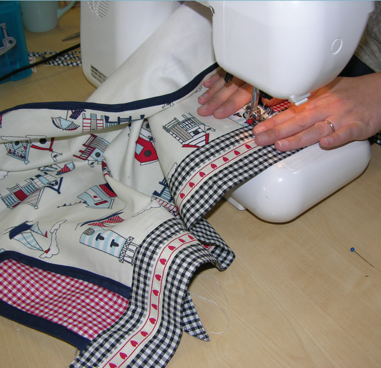 Christmas apron with snowman applique. Pdf sewing pattern by Frocks & Frolics. Fully lined, cute tie backs, free video sew-a-long. In gingham white and blue cotton with red trim bias binding and pockets.