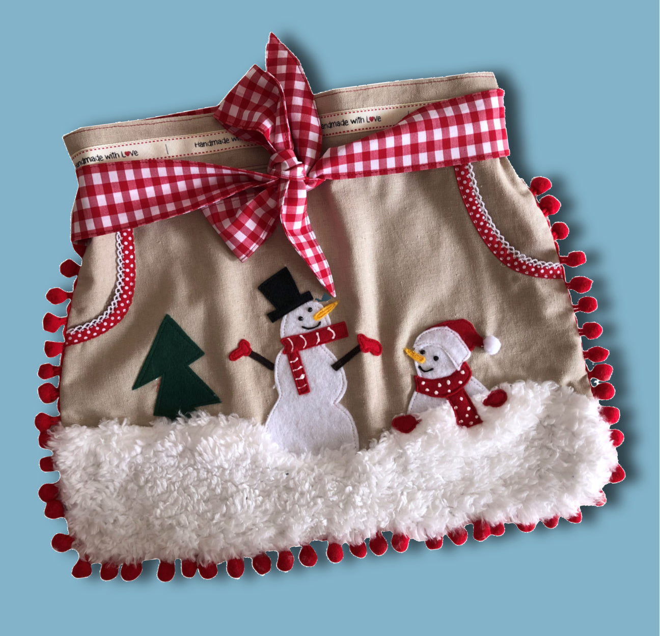 Christmas apron with snowman applique. Pdf sewing pattern by Frocks & Frolics. Fully lined, cute tie backs, free video sew-a-long. In gingham white and blue cotton with red trim bias binding and pockets.
