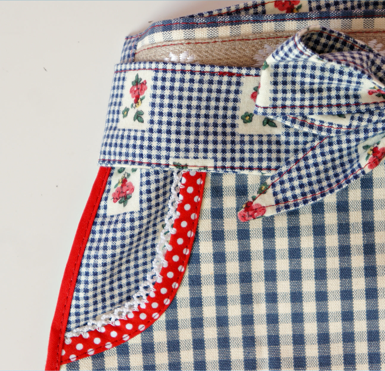 Christmas apron with snowman applique. Pdf sewing pattern by Frocks & Frolics. Fully lined, cute tie backs, free video sew-a-long. In gingham white and blue cotton with red trim bias binding and pockets.