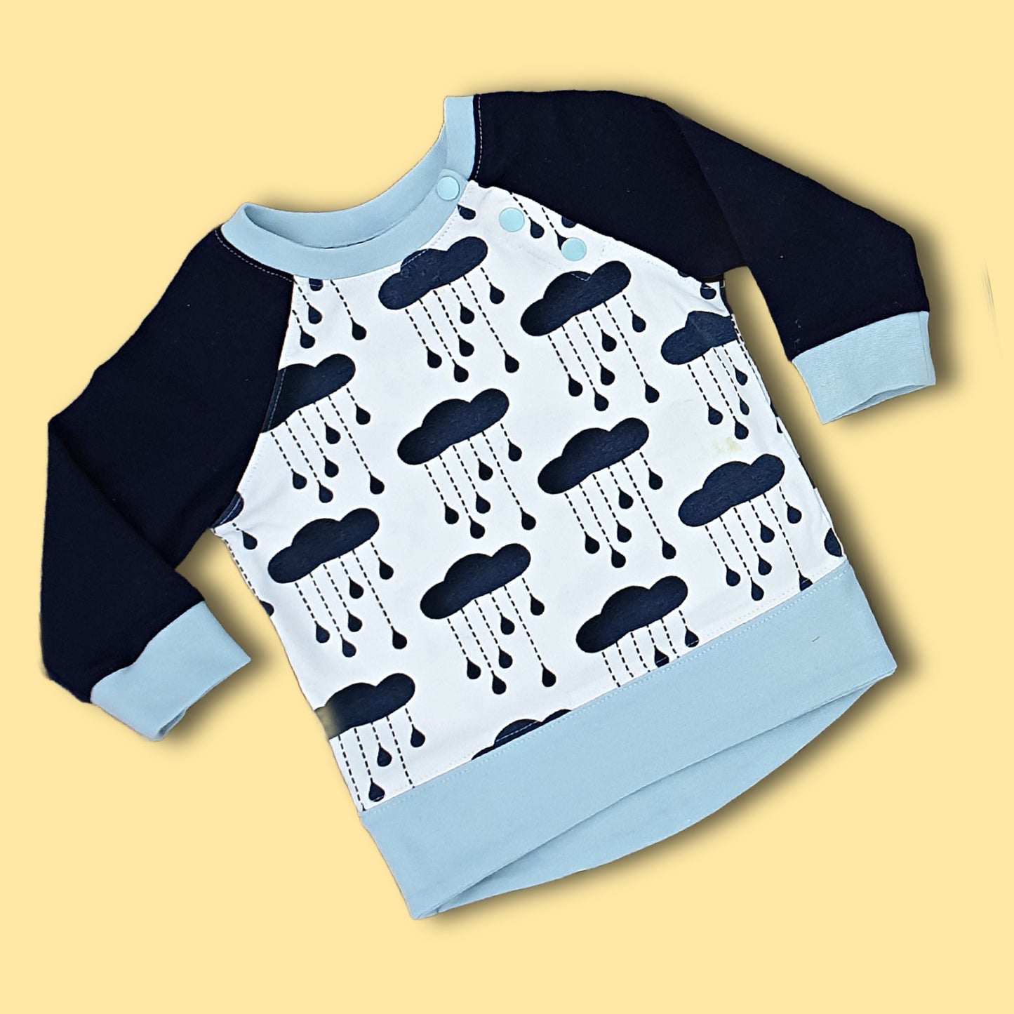 Jelly Bean Sweater, pdf sewing pattern by Frocks & Frolics. Raglan jumper with optional KamSnap opening in the raglan sleeve seam. High low hem trim and cuffs in contrast four way stretch interlock fabric. Includes a free video tutorial.