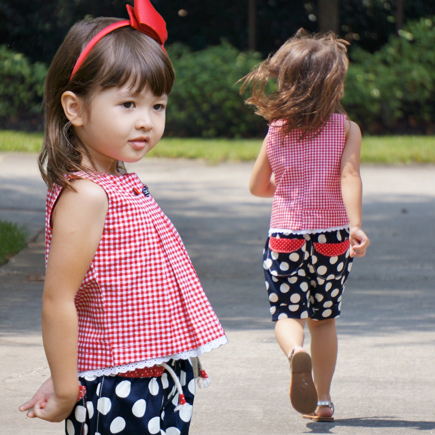 Lily girls dress, pdf sewing pattern by Frocks & Frolics. In red gingham with cute lace trim in white lace. Sleeveless with armhole and neckline facing. The pattern has video tutorials for all the sewing steps.