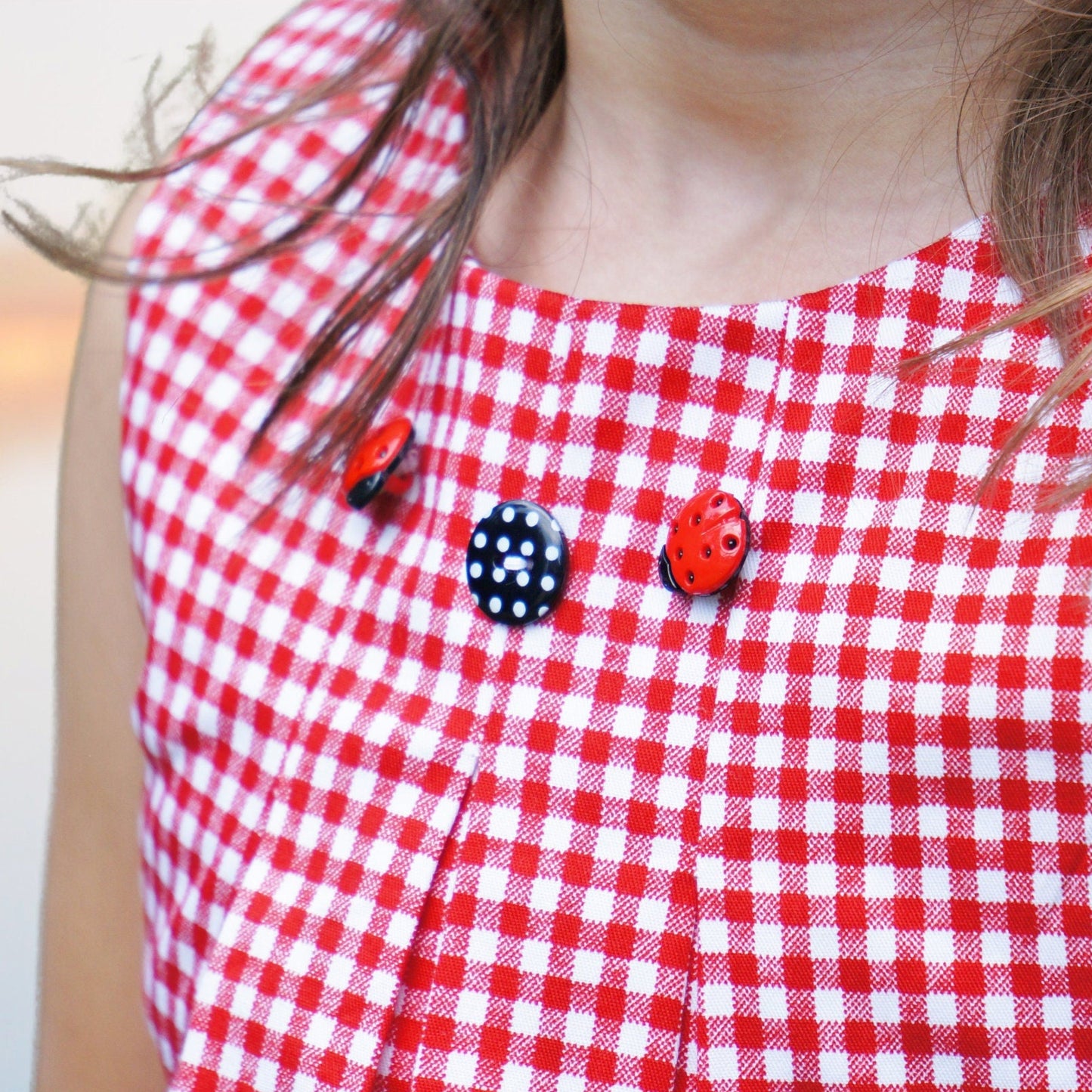Lily girls dress, pdf sewing pattern by Frocks & Frolics. In red gingham with cute lace trim in white lace. Sleeveless with armhole and neckline facing. The pattern has video tutorials for all the sewing steps.