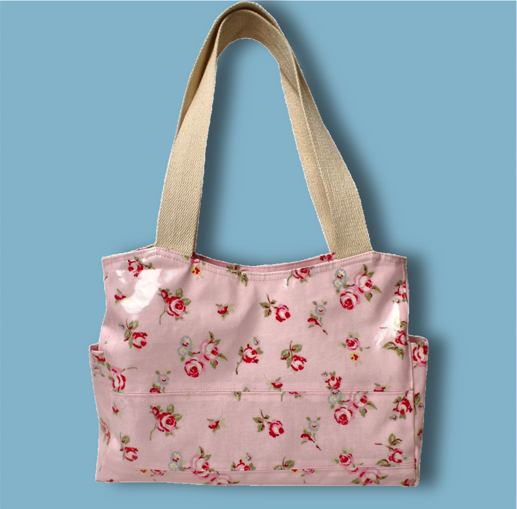 London tote bag pdf sewing pattern by Frocks & Frolics. In laminated oil cloth. Pink with dianty flowers. Wide handles and outside pockets. Fully lined, recessed zip. Comes with a free video course.