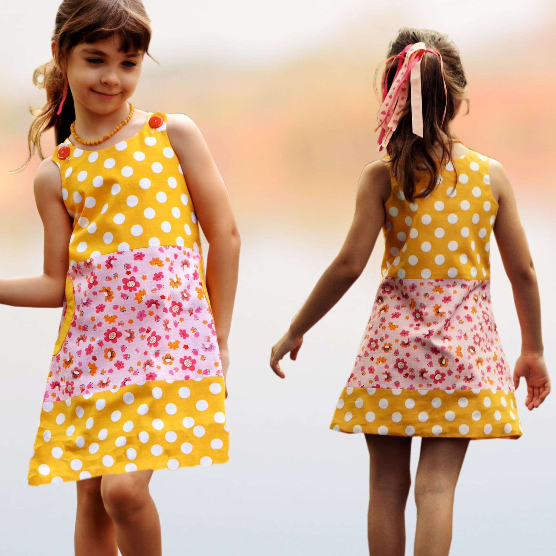 Mimi apron dress pdf sewing pattern. For girls age 1-12. Fully lined with side pockets and cute applique. In white polka dots with mint back base. Colour blocking with a flower print. Front and back view.