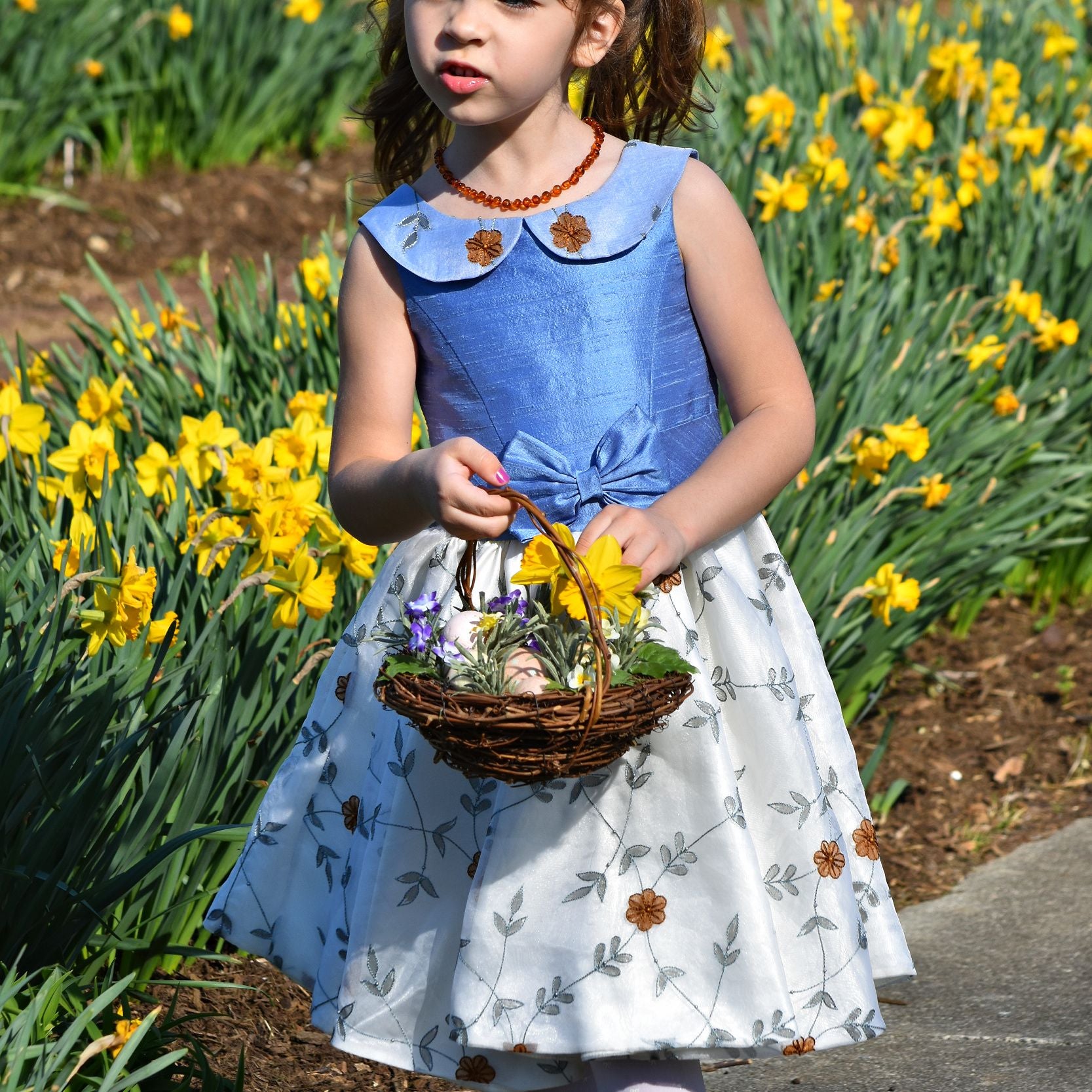 Vivienne dress for girls by Frocks & Frolics. Princess seam bodice, a sleeveless dress with dupion silk bodice and embroidered chiffon circle skirt. The silk Peter Pan collar is also covered in embroidered chiffon. Here the dress has a feature tie and front bow. Concealed zipper.
