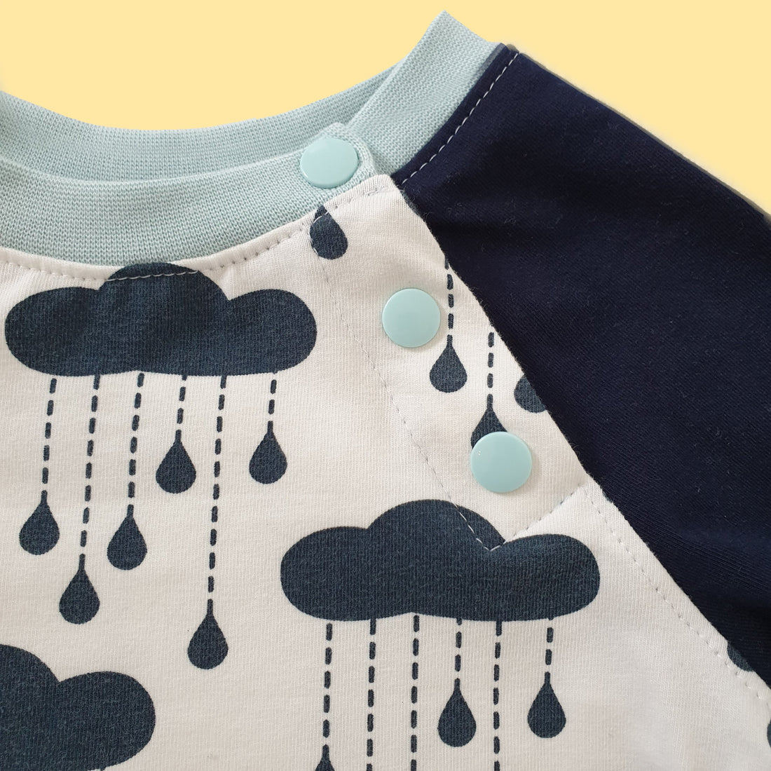 Close-up of KAM snaps set into the raglan seam of a handmade baby sweater