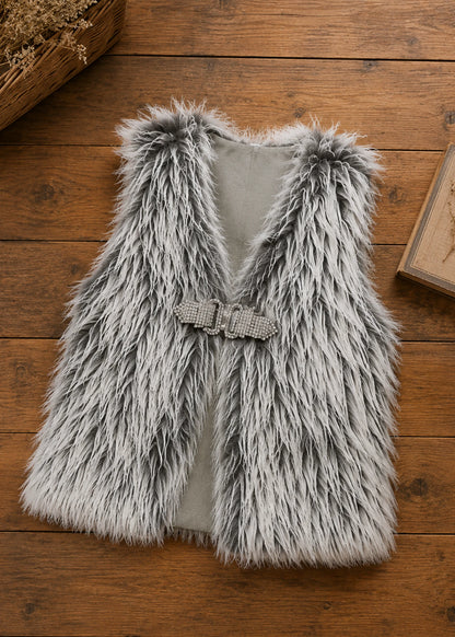 Flat lay of the grey faux fur shaggy vest sewing pattern with sparkly rhinestone buckle closure