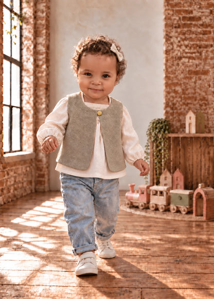 Baby Vest sewing pattern – toddler in sage shaggy reversible vest with white top and jeans