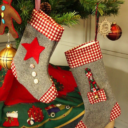 Decorative Christmas stockings with red stars and checkered patterns hanging on a tree.