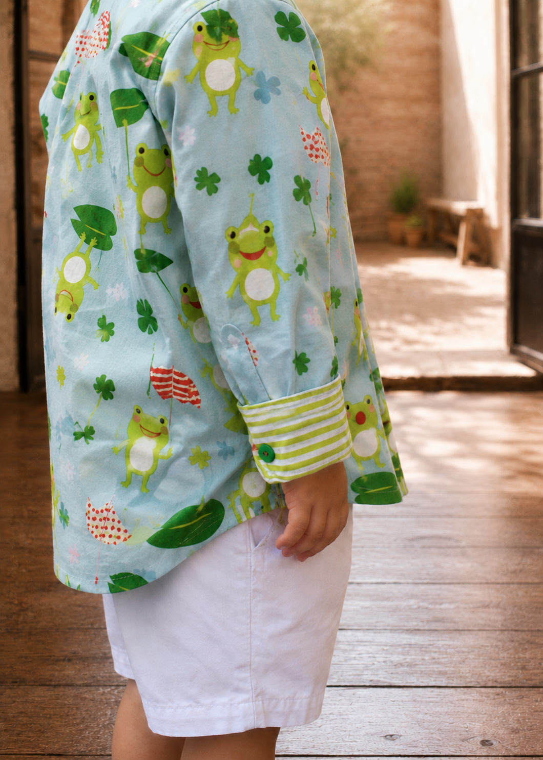 Close-up of a long-sleeve Cool Shirt in a frog and clover print fabric showing the striped cuff detail