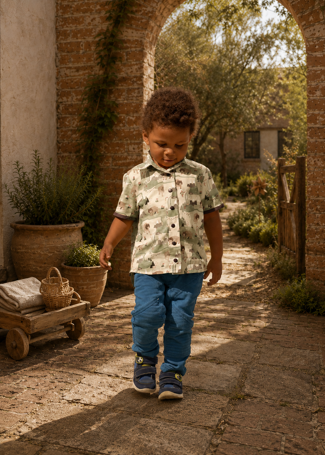 Back view of a toddler walking away in a bear and mountain print Cool Shirt with blue pants