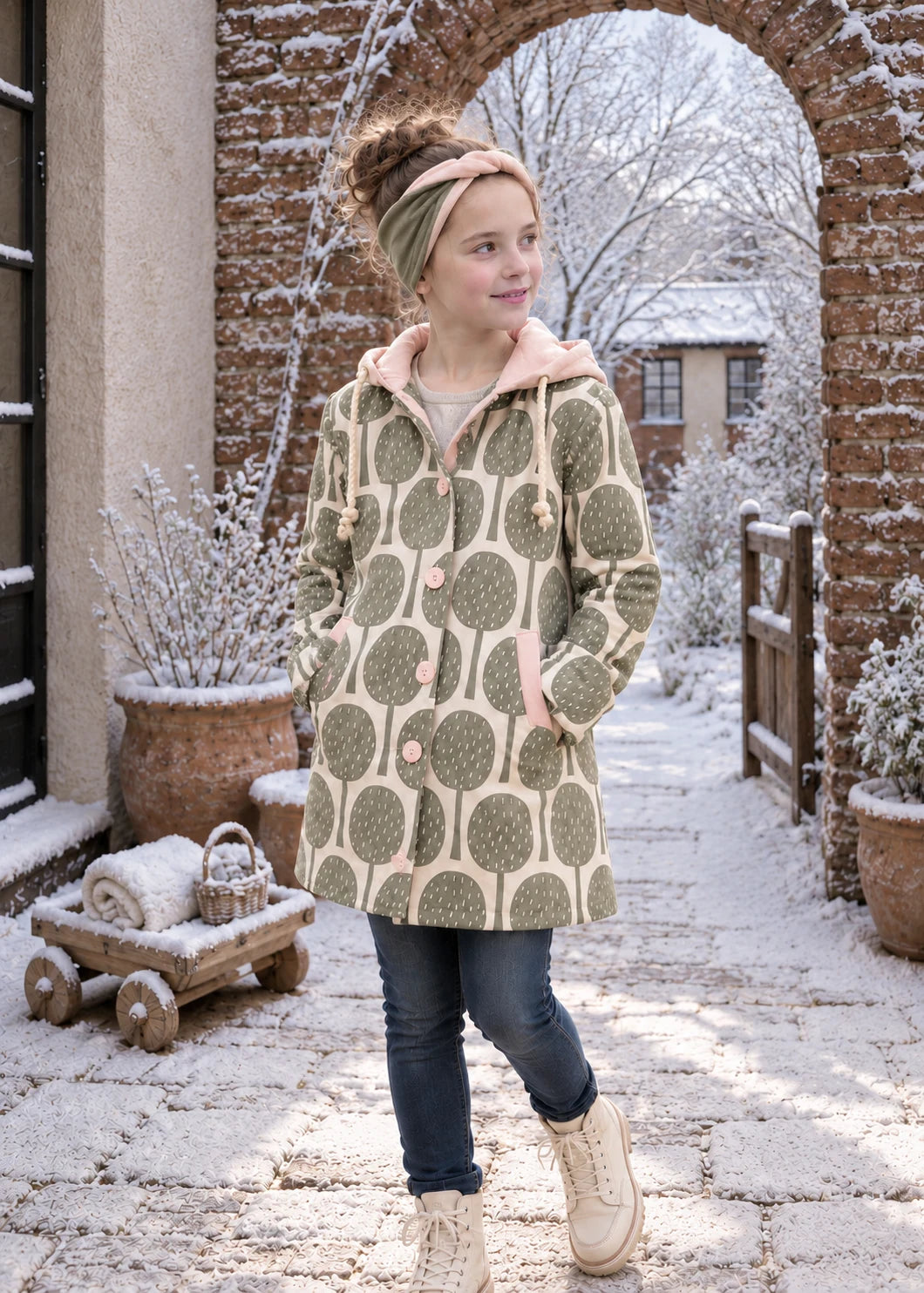 Dakota Pea Coat sewing pattern – leaf print jersey coat with pink-lined hood in a snowy garden archway