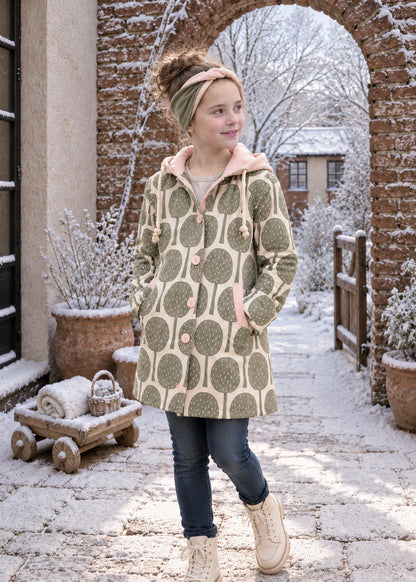 Dakota Pea Coat sewing pattern – leaf print jersey coat with pink-lined hood in a snowy garden archway