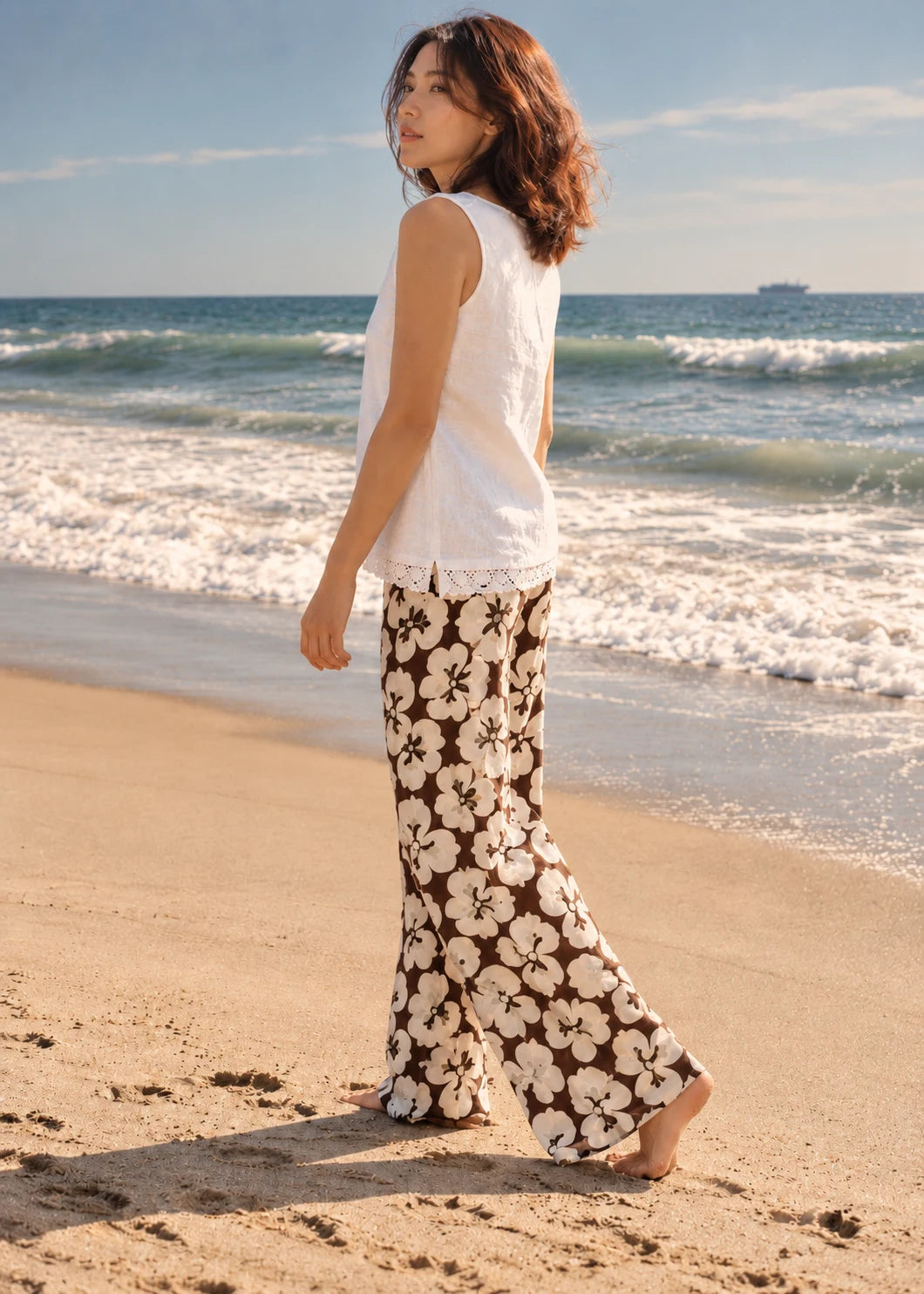 Devon Pants sewing pattern – side view of flowing patterned beach pants with a white tank, walking on the sand