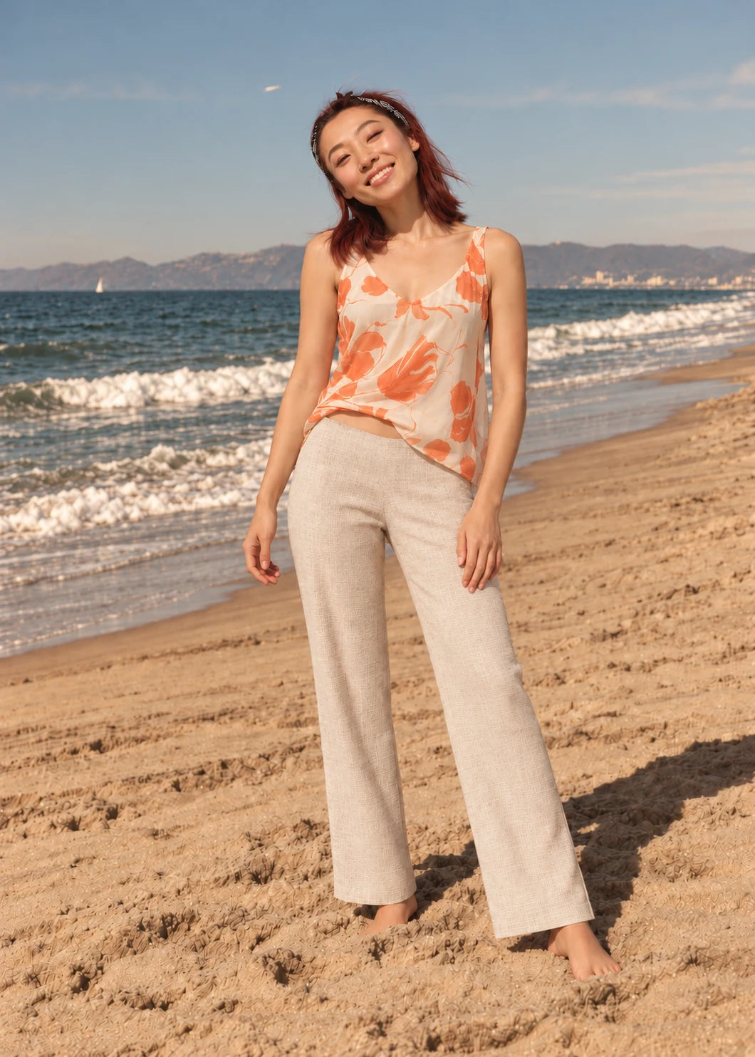 Devon Pants sewing pattern – front view of hip-height beige linen trousers with a coral floral cami by the sea