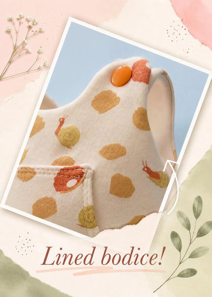 A close-up of a baby bodice or dress panel with a cream base, mustard and orange polka dots, and small illustrated motifs, shown inside a tilted photo frame on a pastel styled background with the text 'Lined bodice!'.