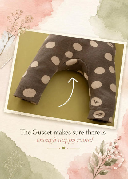A U-shaped baby nappy guard with beige polka dots on a dark gray fabric, shown inside a tilted photo frame with a white arrow pointing to it. The graphic includes the text 'The Gusset makes sure there is enough nappy room!' on a watercolor-style beige background with pink and green accents.