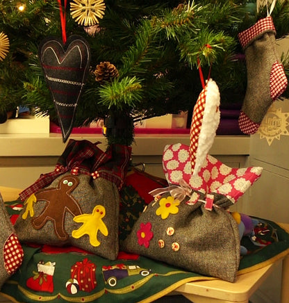 Decorative Christmas pillows with gingerbread men and other designs on a table in front of a decorated tree.