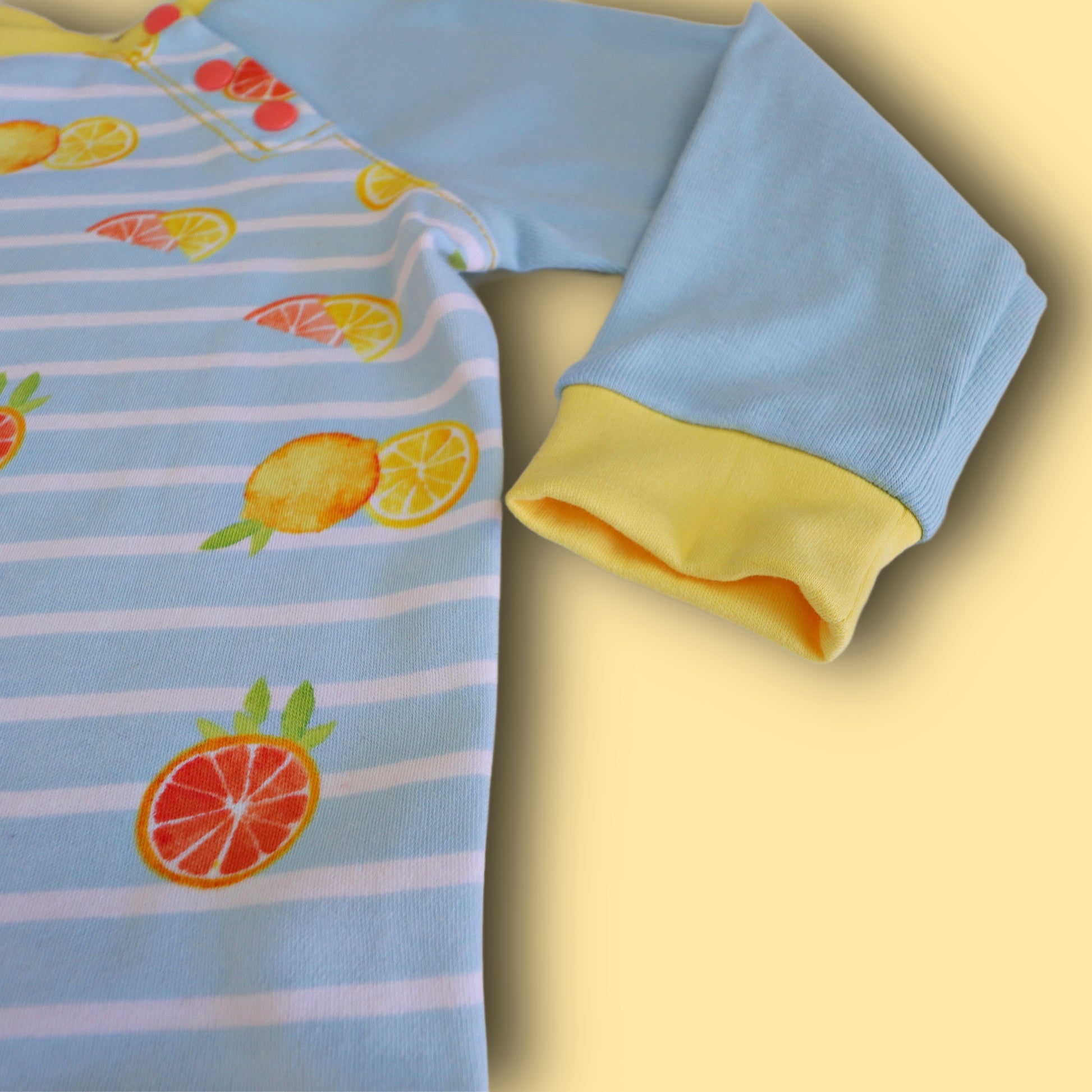 Jelly Bean Sweater, pdf sewing pattern by Frocks & Frolics. Raglan jumper with optional KamSnap opening in the raglan sleeve seam. High low hem trim and cuffs in contrast four way stretch interlock fabric. Includes a free video tutorial.