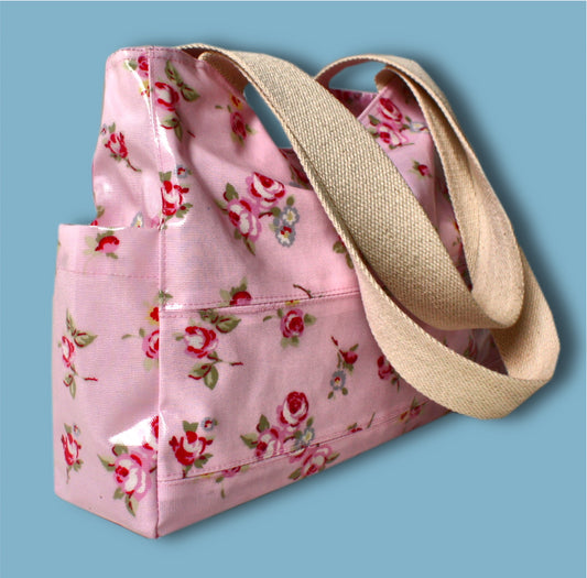 London tote bag pdf sewing pattern by Frocks & Frolics. In laminated oil cloth. Pink with dianty flowers. Wide handles and outside pockets. Fully lined, recessed zip. Comes with a free video course.