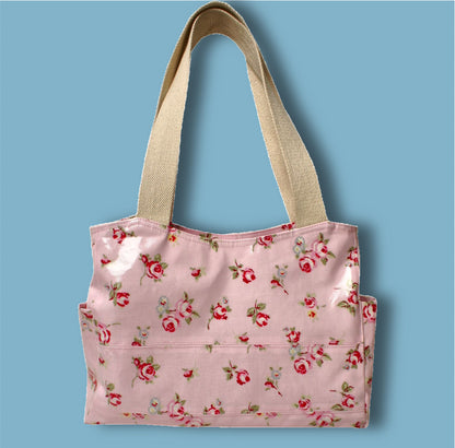 London tote bag pdf sewing pattern by Frocks & Frolics. In laminated oil cloth. Pink with dianty flowers. Wide handles and outside pockets. Fully lined, recessed zip. Comes with a free video course.