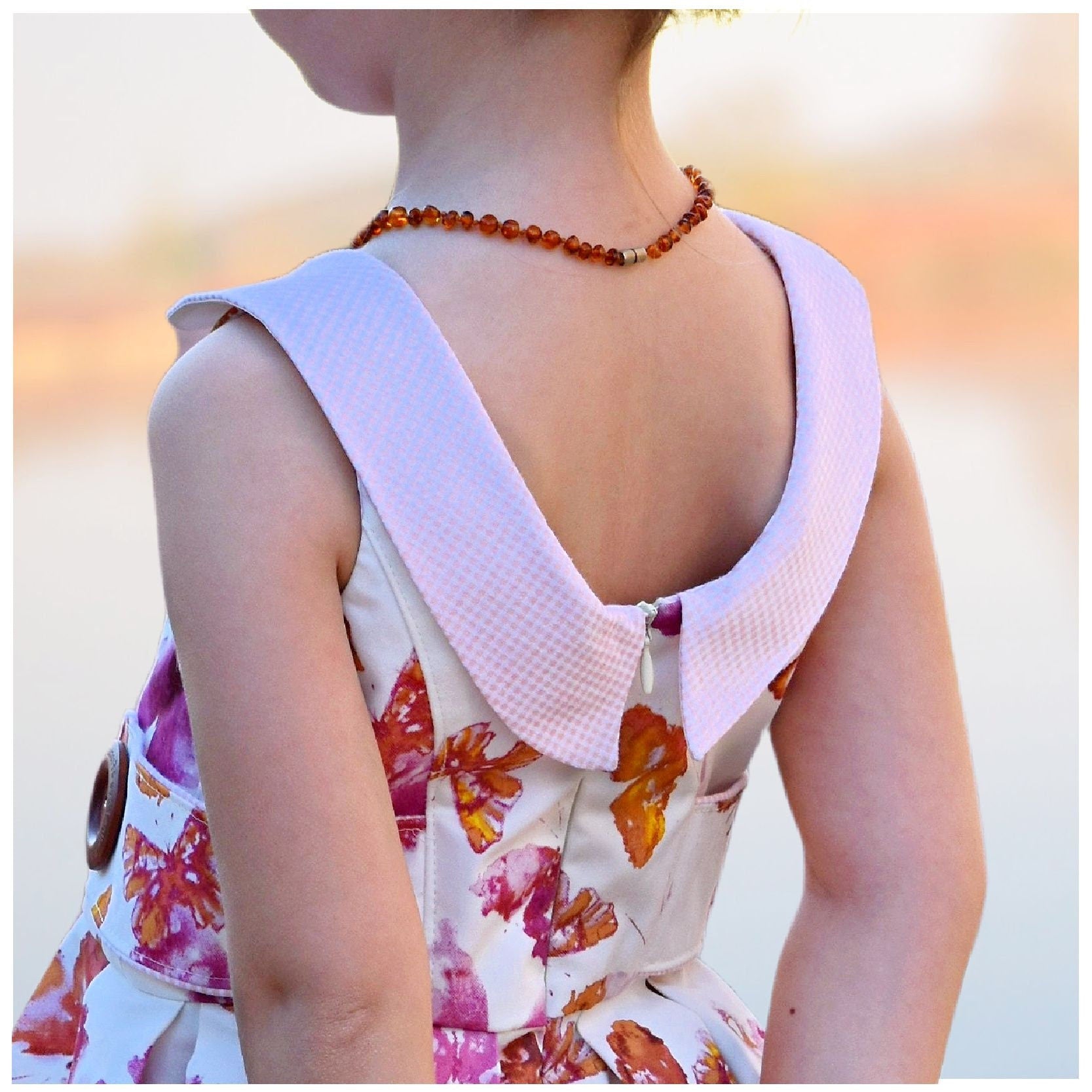 Vivienne dress for girls by Frocks & Frolics. Princess seam bodice, a sleeveless dress printed denim. Peter Pan collar with lower cut back. Pleated skirt. Large feature tabs with oversized button. Concealed zipper. 