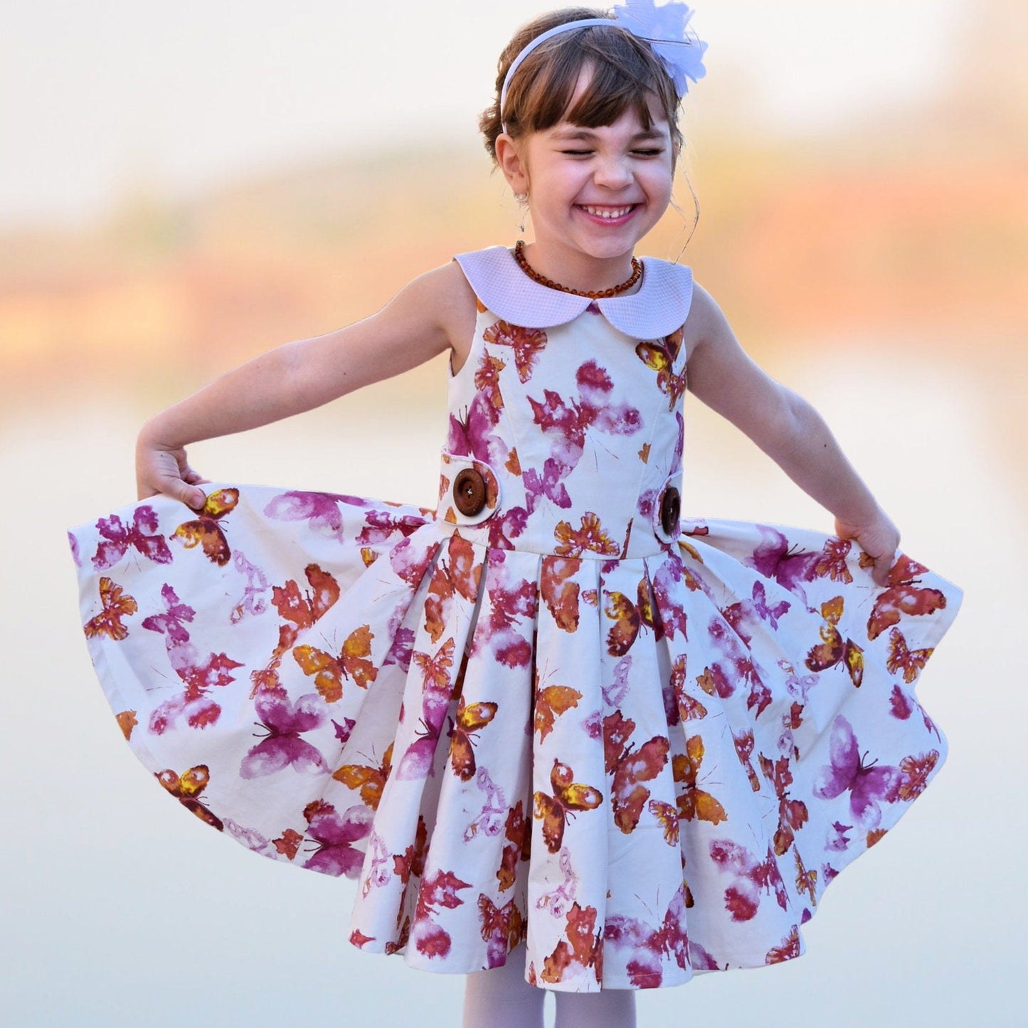 Vivienne dress for girls by Frocks & Frolics. Princess seam bodice, a sleeveless dress printed denim. Peter Pan collar with lower cut back. Pleated skirt. Large feature tabs with oversized button. Concealed zipper. 