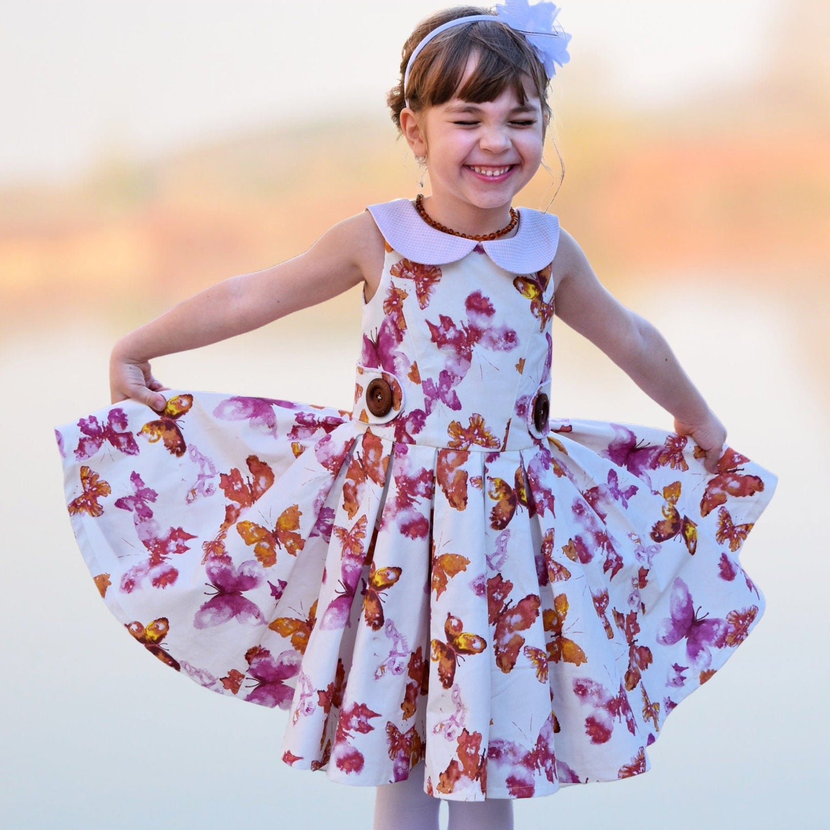 Vivienne dress for girls by Frocks & Frolics. Princess seam bodice, a sleeveless dress printed denim. Peter Pan collar with lower cut back. Pleated skirt. Large feature tabs with oversized button. Concealed zipper. 
