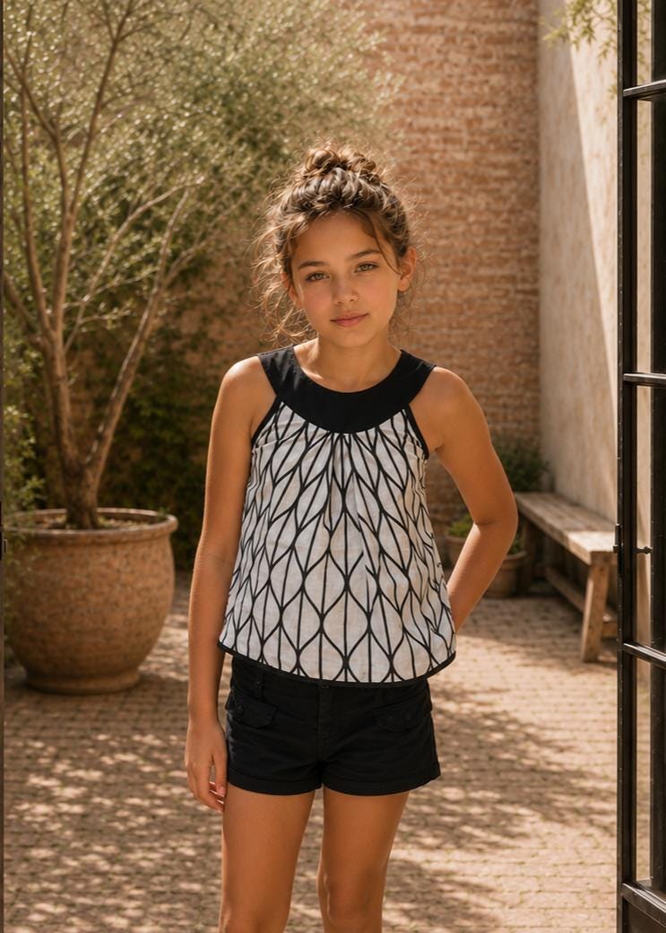 Frocks & Frolics Kitty top sewing pattern – sleeveless black and white print top with black round yoke, worn with shorts