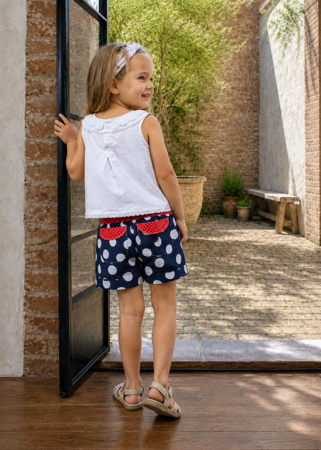Frocks & Frolics Maisy shorts sewing pattern – back view of navy polka dot shorts with red pocket flaps