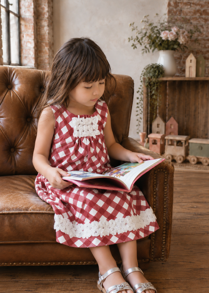 Girl sitting on a leather sofa reading, wearing a terracotta check dress with lace hem made with the Lily dress PDF sewing pattern by Frocks & Frolics