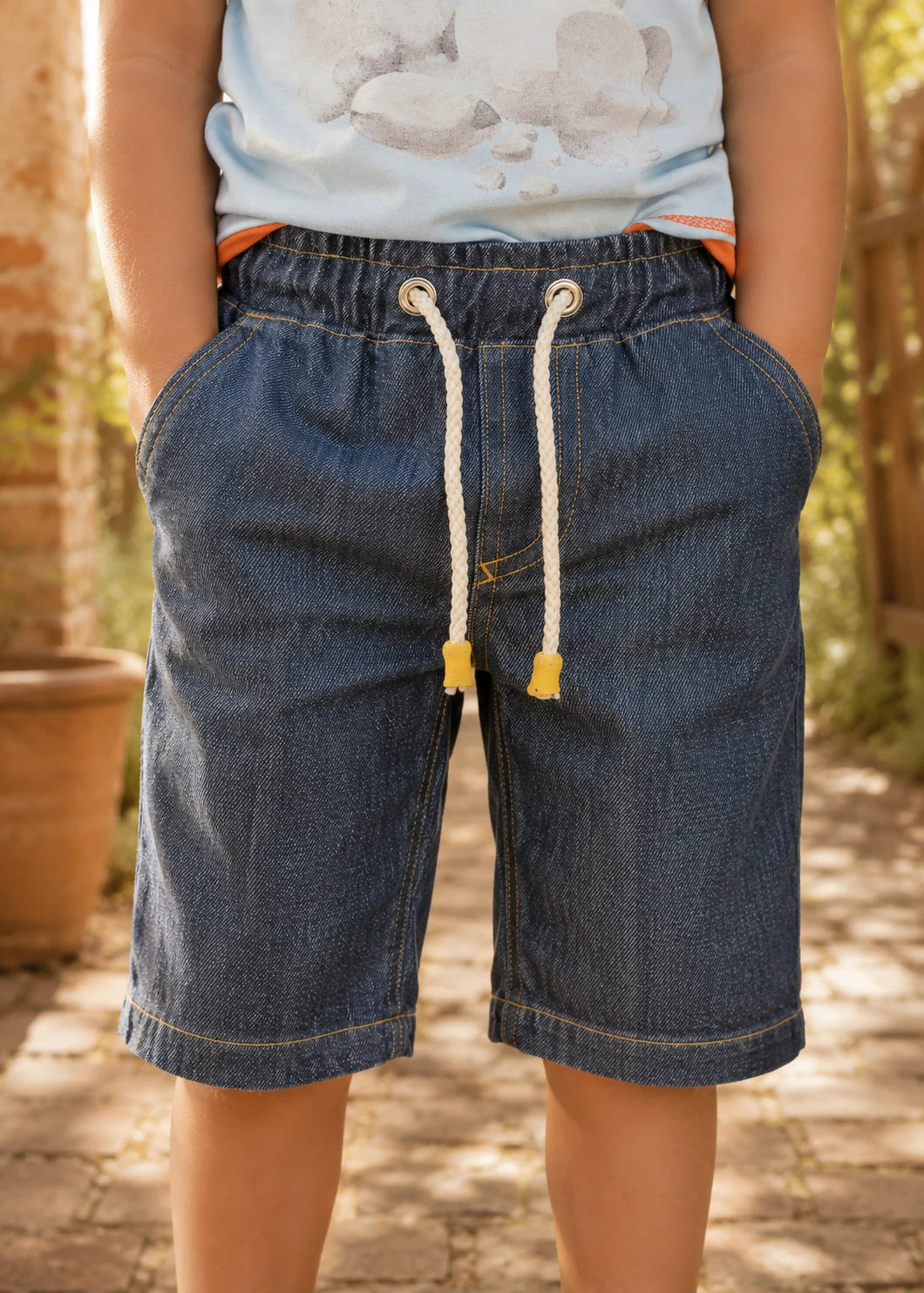 Close-up front view of the Oscar Shorts denim waistband showing the elastic casing, metal eyelets, and cotton rope drawstring with wooden cord ends