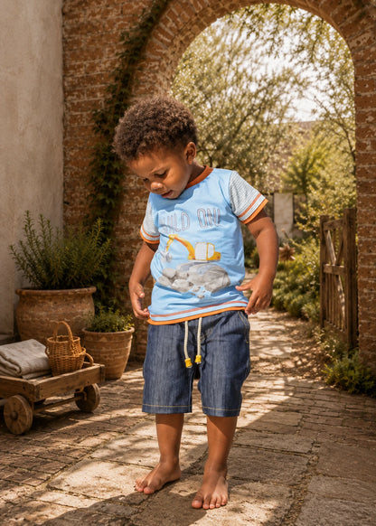 Close-up of a child wearing Oscar Shorts in a football team-print fabric, showing the drawstring waistband with metal eyelets and rope cord ends