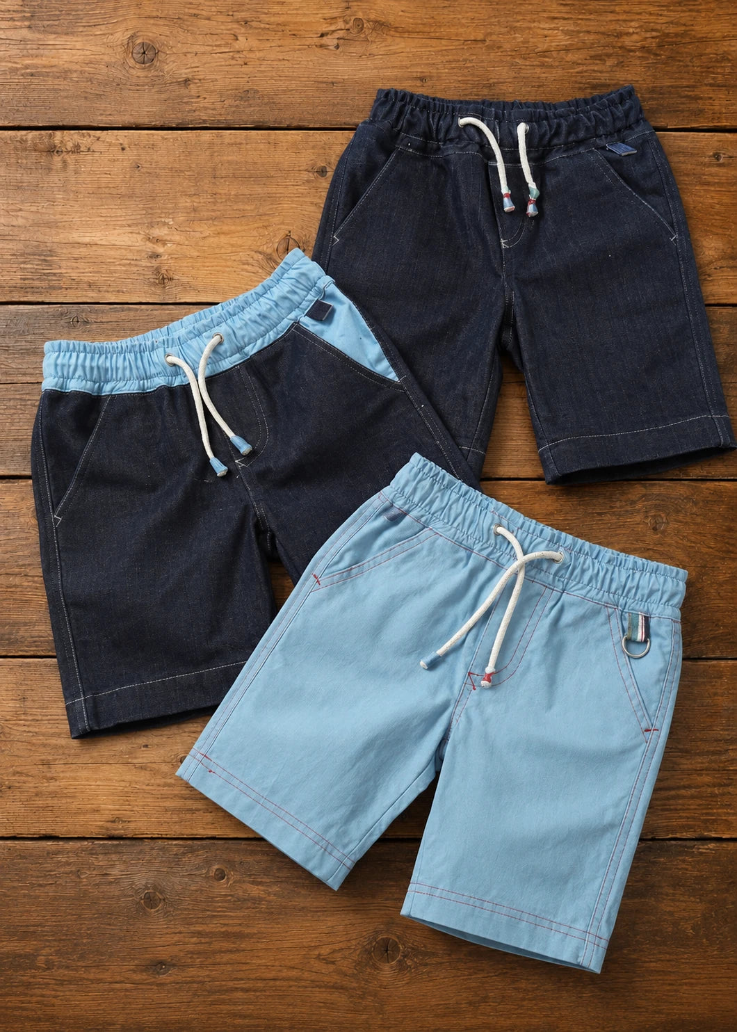 Flat lay of three finished Oscar Shorts in dark denim, light denim, and light blue chambray, each with drawstring waistband and side pockets